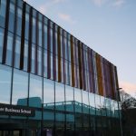 L'architecture moderne de l'Alliance Manchester Business School se reflète dans sa façade vitrée au crépuscule.