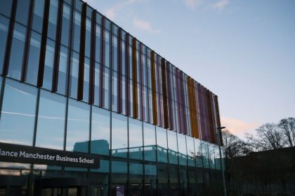 L'architecture moderne de l'Alliance Manchester Business School se reflète dans sa façade vitrée au crépuscule.
